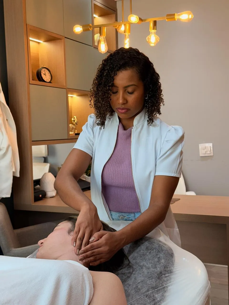 Dra. Isadora fazendo massagem no rosto e no pescoço de uma paciente no Espaço Alento